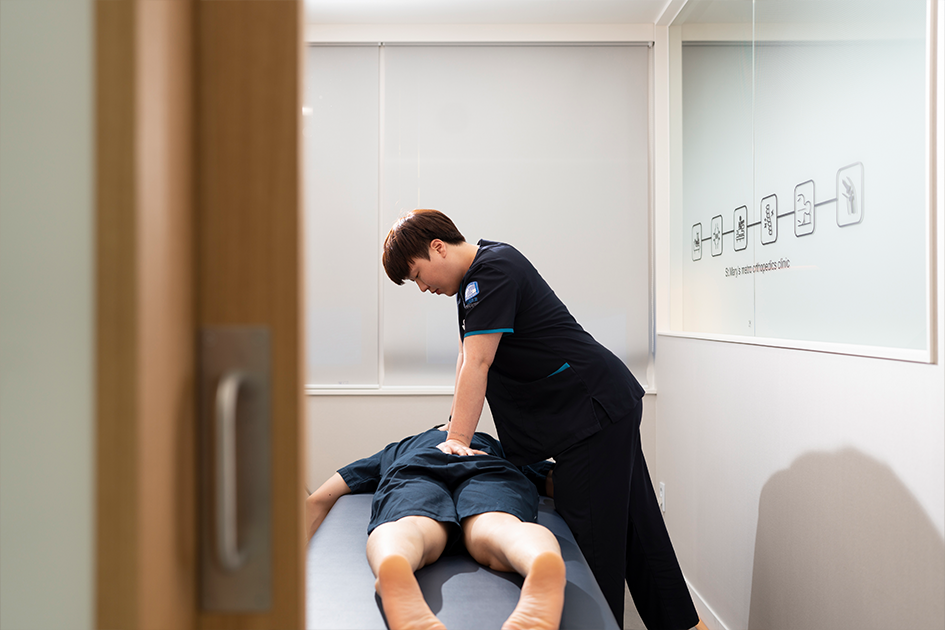 엎드린 환자의 척추를 도수치료하는 모습